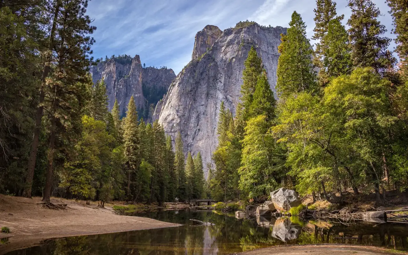 A granite cliff above a river, with conifers along both banks